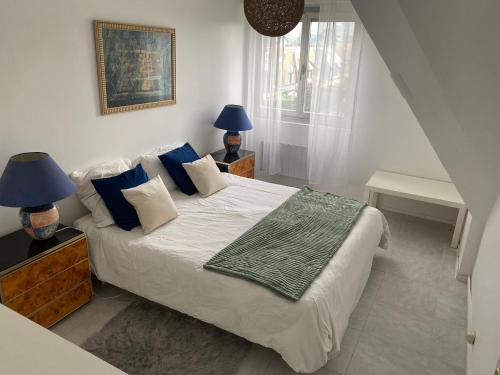 1 dormitorio con 1 cama grande con almohadas azules en Picsine, Tennis résidence sévigné 300m mer, en Deauville