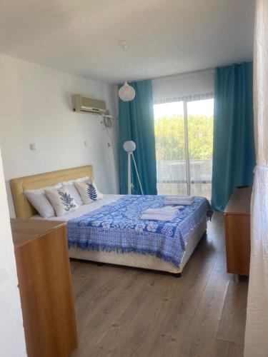 Schlafzimmer mit einem Bett mit blauer Bettwäsche und einem Fenster in der Unterkunft Deniz Kızı Otel Çeşme in Cesme