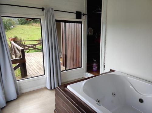 a bathroom with a tub and a large window at Hospedaria Kayser Haus in Urubici