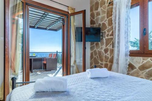a bedroom with a bed and a view of the ocean at Villa Calliopé avec vue imprenable, jardin et piscine privée in Glóssa