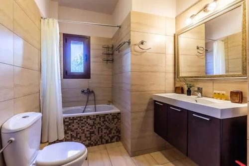 a bathroom with a sink and a tub and a toilet at Villa Calliopé avec vue imprenable, jardin et piscine privée in Glóssa
