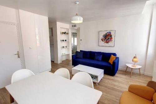 een woonkamer met een blauwe bank en witte stoelen bij HENRI CAMILLE REAL ESTATE - Bambou- One bedroom center in Cannes