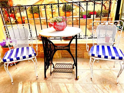 una mesa y 2 sillas con un jarrón en el balcón en Yellow House Oropos en Néa Palátia