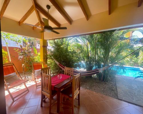 a room with a table and chairs and a hammock at The Inner Light Yoga Lodge in Sámara