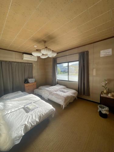 Habitación de hotel con 2 camas y ventana en 高島市マキノ町民泊お得, en Takashima