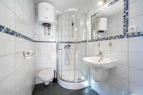 uma casa de banho com um chuveiro, um WC e um lavatório. em Błękitne domki przy morzu em Międzywodzie