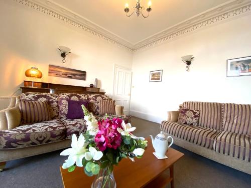 a living room with a couch and a table with flowers at Dairsie Sea View in Rothesay