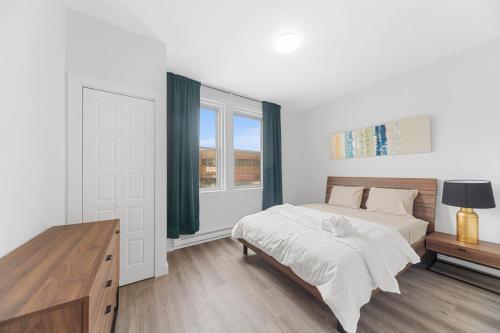 a white bedroom with a bed and a window at Stonewall Suites in Montréal
