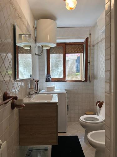 bagno con lavandino, servizi igienici e finestra di Le Bouganville apartment a Santa Teresa di Gallura