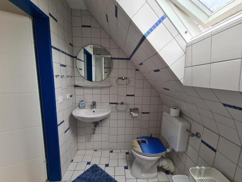 uma casa de banho com um WC, um lavatório e um espelho. em Ferienhaus am Kurpark-Norddeich strandnah em Norden