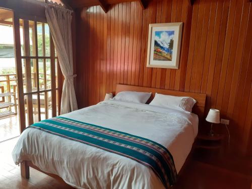 1 dormitorio con 1 cama con pared de madera en Chontaqui Eco-Lodge, en Oxapampa
