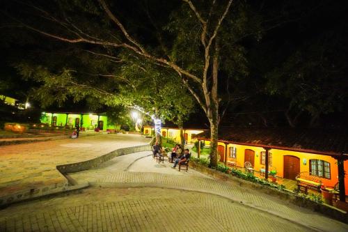 een groep mensen die 's nachts op banken in een park zitten bij La Arboleda Colonial Hotel in El Molino