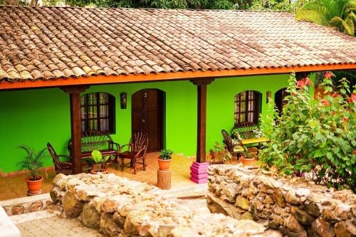 a green house with a stone wall at La Arboleda Colonial Hotel in El Molino