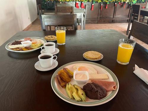a table with a plate of breakfast food and orange juice at La Arboleda Colonial Hotel in El Molino
