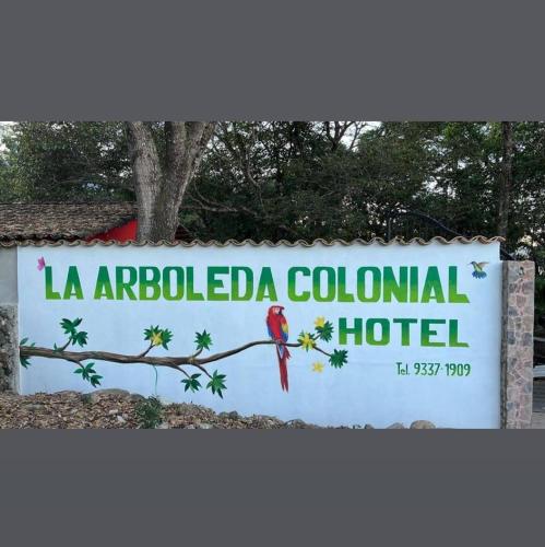 een bord voor een hotel met een rode vogel op een tak bij La Arboleda Colonial Hotel in El Molino