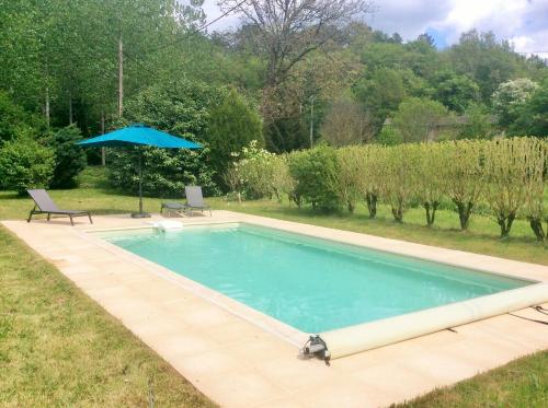 une piscine dans une cour avec un parasol dans l'établissement Gîte La Petite Fagette, à Frayssinet-le-Gélat