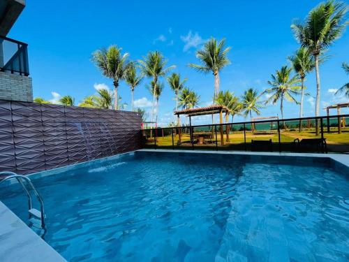 una piscina con palmeras en el fondo en Amaranth Beach Class - Miramar Hospedagens, en Cabedelo