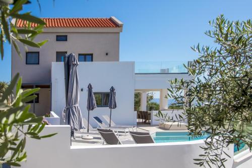 a pool with chairs and umbrellas next to a building at Casa Galatas in Galatás