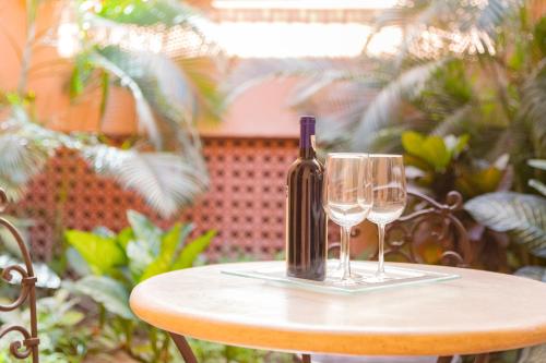 a bottle of wine and two glasses on a table at HOTEL COLLI in San José del Cabo