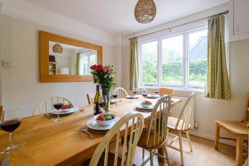 uma sala de jantar com uma mesa de madeira e uma grande janela em 9 Whinlands em Thorpeness
