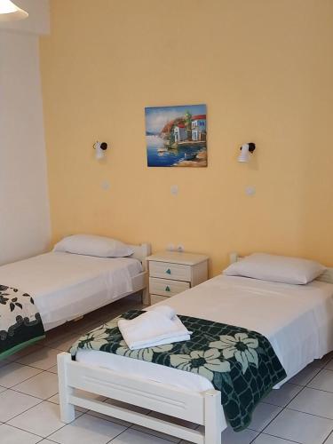 a bedroom with two beds and a picture on the wall at Odyseas Studios in Lourdhata