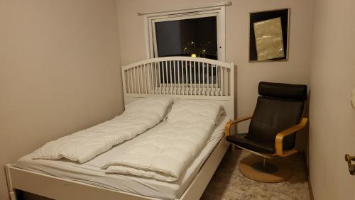 łóżko i krzesło w pokoju z oknem w obiekcie Laksevåg Apartment w Bergen