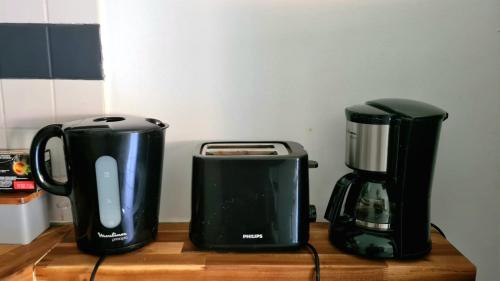 two black appliances sitting on a wooden counter at Studio moderne, centre-ville, au calme, parking privé in La Possession