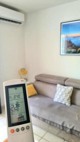 a clock in a living room with a couch at Studio moderne, centre-ville, au calme, parking privé in La Possession