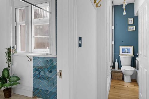 a bathroom with blue walls and a toilet at Flat 2 Fairfax Place - Modern stylish flat with plenty of charm in central Dartmouth in Dartmouth