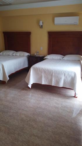 two beds in a hotel room with white comforter at Hotel la finca in Ezequiel Montes