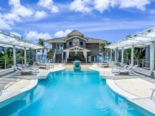 a swimming pool with chairs in front of a house at Ocean Escape Resort & Spa in Rarotonga