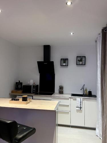 uma cozinha com armários brancos e uma cadeira preta em Le 37 - Appartement privatif avec Jaccuzi em Saint-Étienne