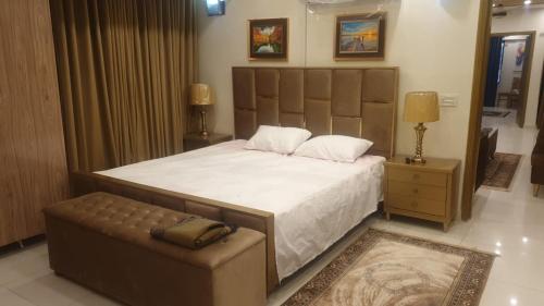 a bedroom with a large bed and a chair at AQZ Three-bedroom apartment in Islamabad