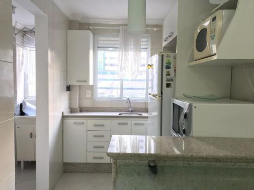 Una cocina blanca con fregadero y refrigerador. en Frederico, en Meia Praia