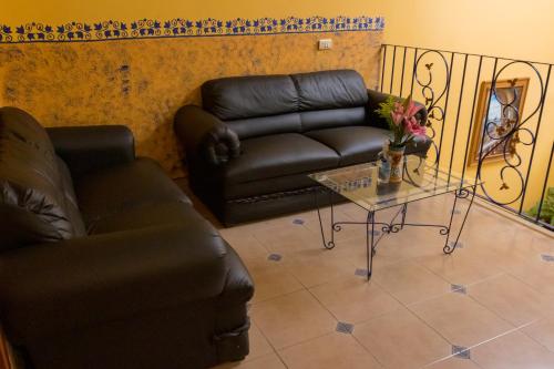 ein Wohnzimmer mit einem Ledersofa und einem Tisch in der Unterkunft Hotel del Parque Naolinco in Naolinco