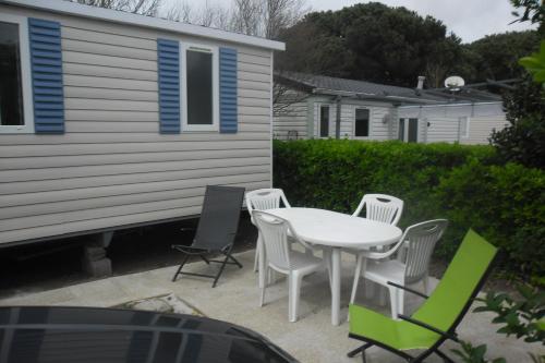a patio with a table and chairs and a house at Mobil home in La Cotinière