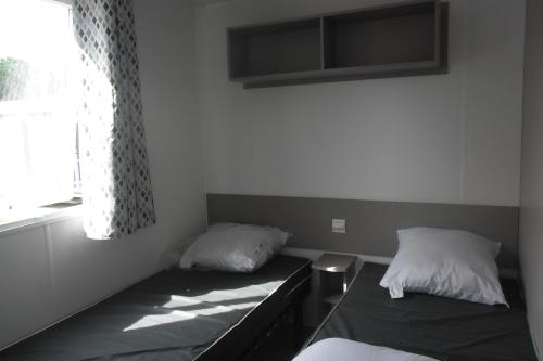 Cette chambre comprend 2 lits et une fenêtre. dans l'établissement Mobil home, à La Cotinière