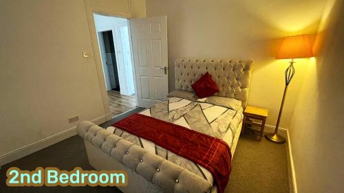 a bedroom with a bed with a red pillow on it at Two Bedroom Entire Flat, Luxury but Affordable Next to M90 in Fife