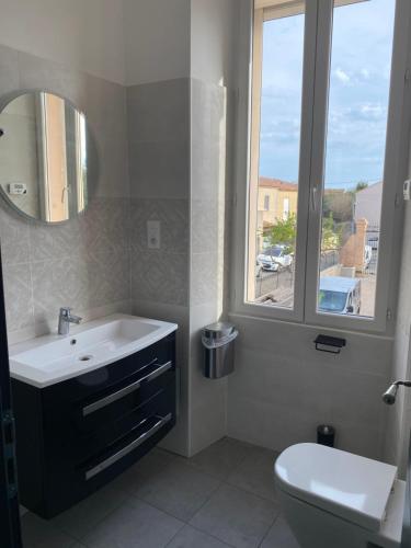 a bathroom with a sink and a toilet and a window at Appart'Hôtel Sous Les Pins in Martigues