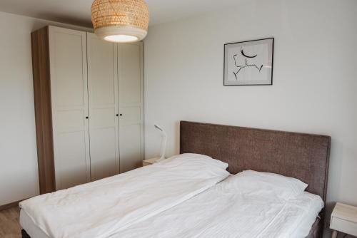 een slaapkamer met een bed met witte lakens en een kast bij Soft Loft in Szczecinek