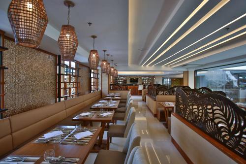 a restaurant with wooden tables and chairs and windows at Best Western Plus The Ivywall Hotel - Palawan in Puerto Princesa City