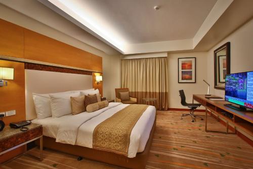 a hotel room with a bed and a desk and a television at Best Western Plus The Ivywall Hotel - Palawan in Puerto Princesa City