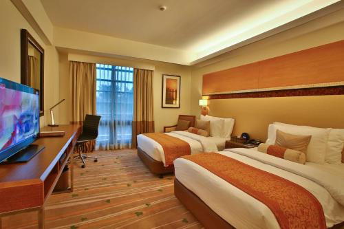 a hotel room with two beds and a flat screen tv at Best Western Plus The Ivywall Hotel - Palawan in Puerto Princesa City