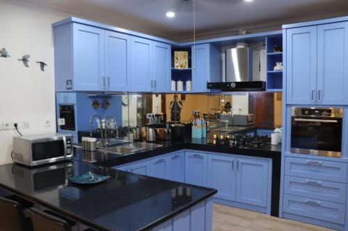 a kitchen with blue cabinets and a black counter top at Villa Munjul Indah - Majalengka in Jatipamor