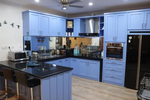 a blue kitchen with black counter tops and appliances at Villa Munjul Indah - Majalengka in Jatipamor