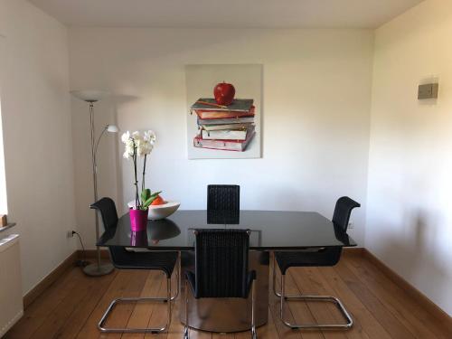 a dining room table with chairs and an apple on a painting at Privatzimmer Boardinghouse/Messe Düsseldorf in Viersen