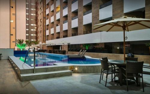 una piscina en un edificio con mesa y sombrilla en Gold Flat - Miramar Hospedagens en João Pessoa