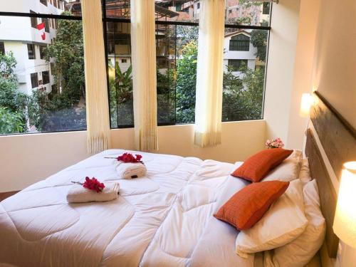 a large white bed with two pillows and two windows at Centro Espiritual Hostal Inti Wasi in Machu Picchu