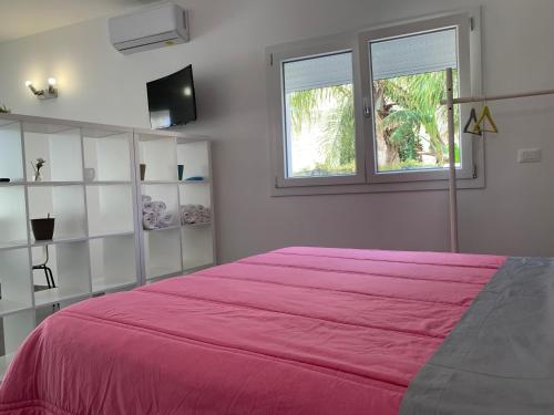 ein Schlafzimmer mit einem rosa Bett und einem Fenster in der Unterkunft White House monolocale in Avola