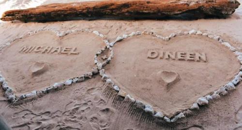two hearts written in the sand next to a log at Ocean Escape Resort & Spa in Rarotonga
